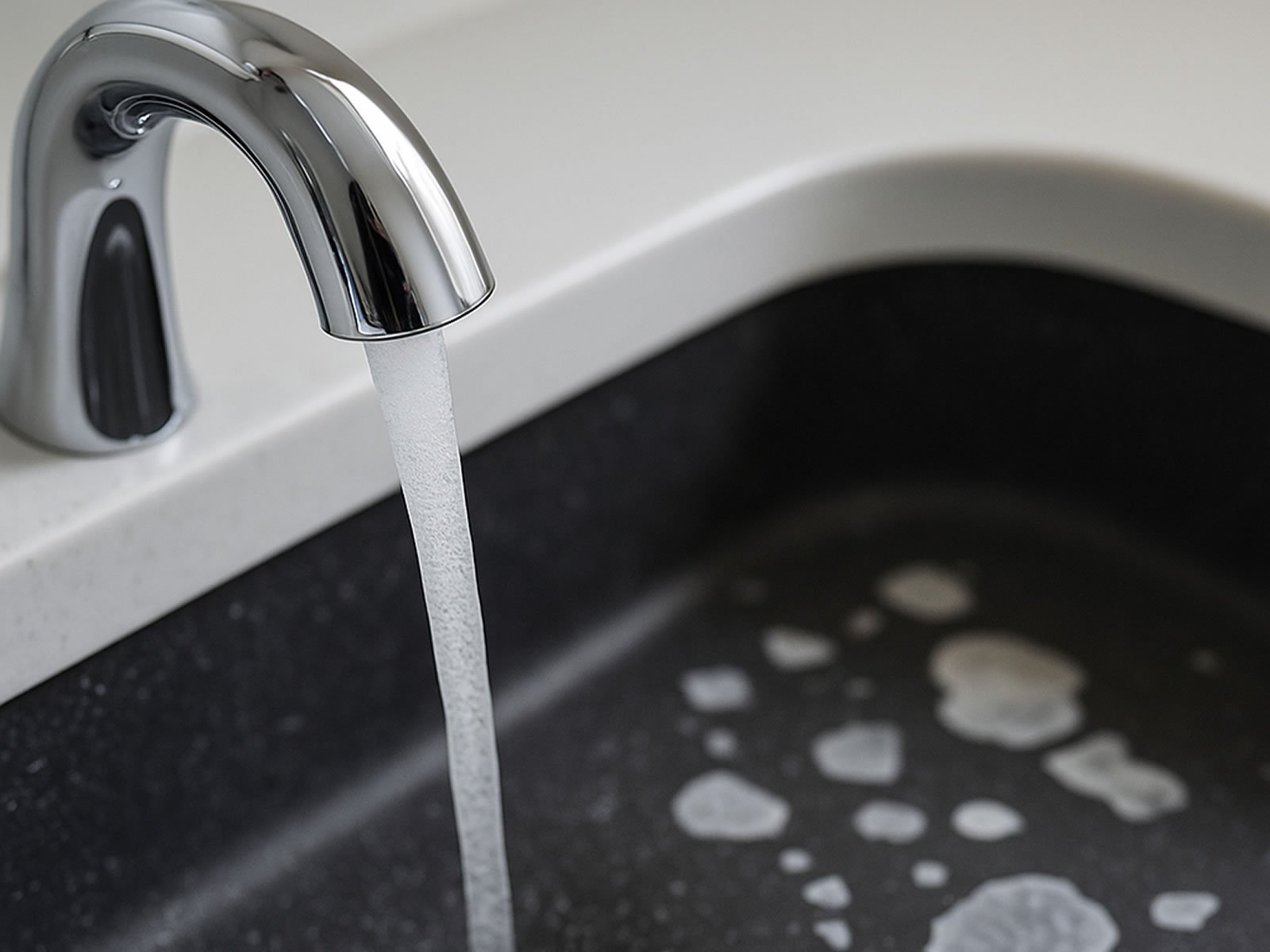 White silica film deposits on a chrome faucet and sink